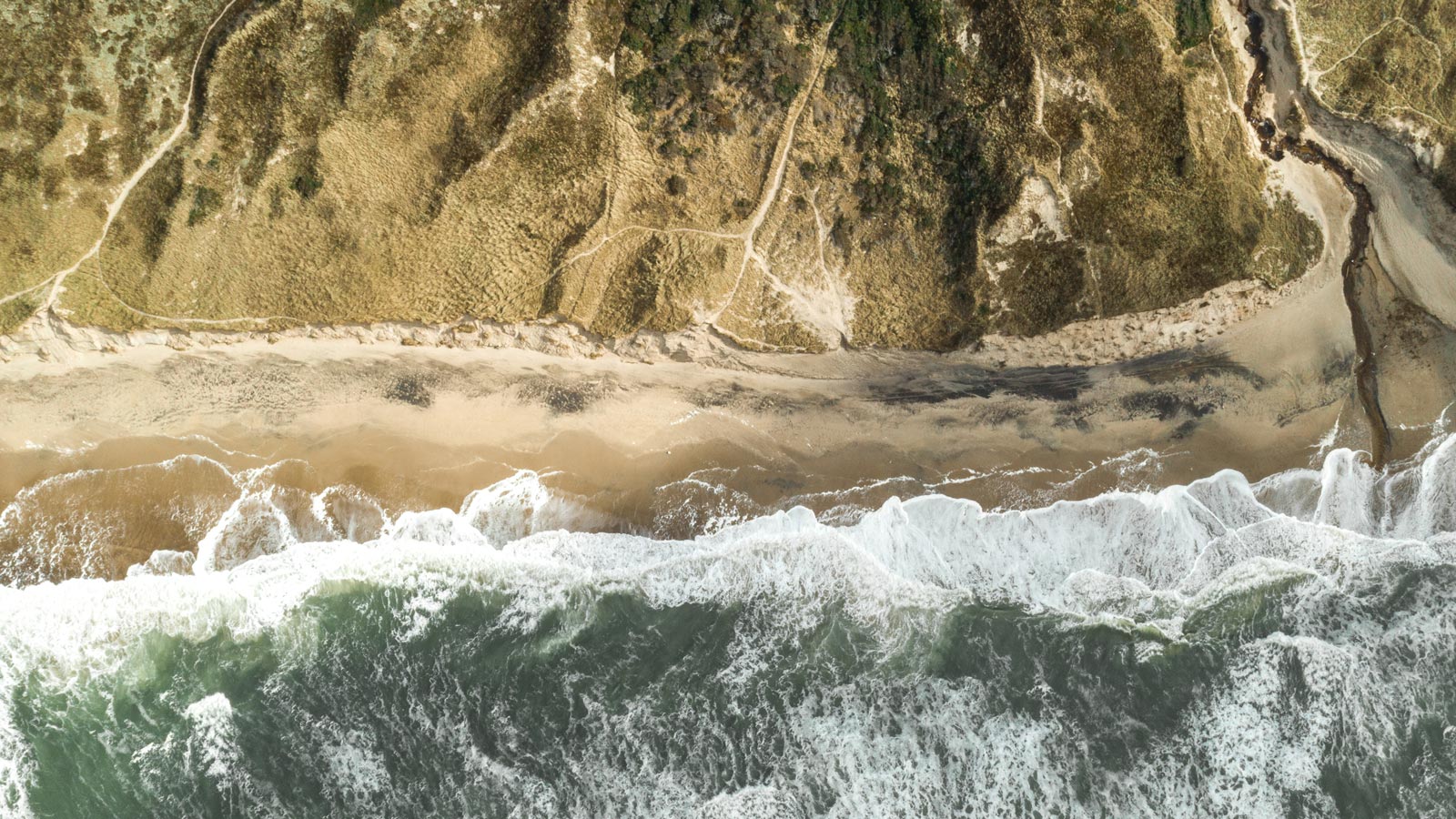 Dronefoto af Klitmøllers kystlinje med hav og klitter